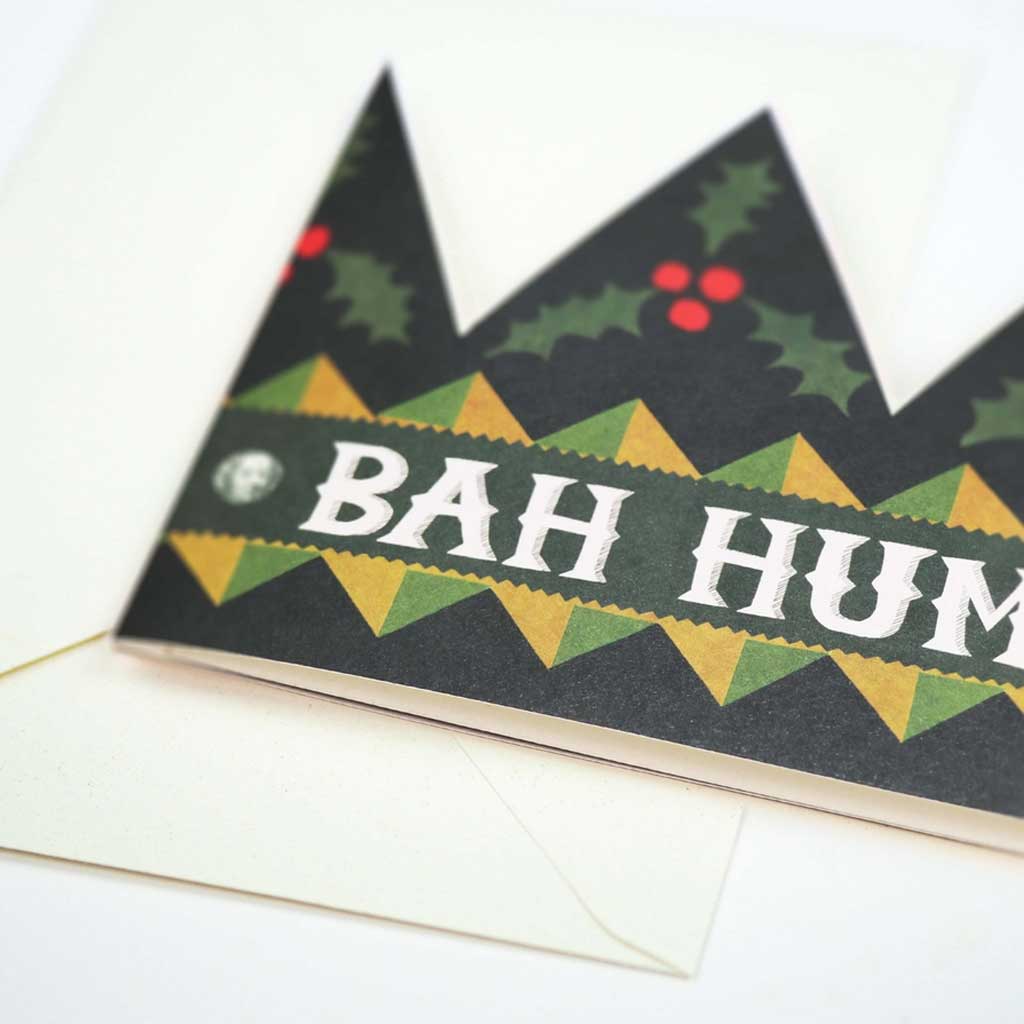 Close up of die-cut holiday greeting card crown with text bah humbug