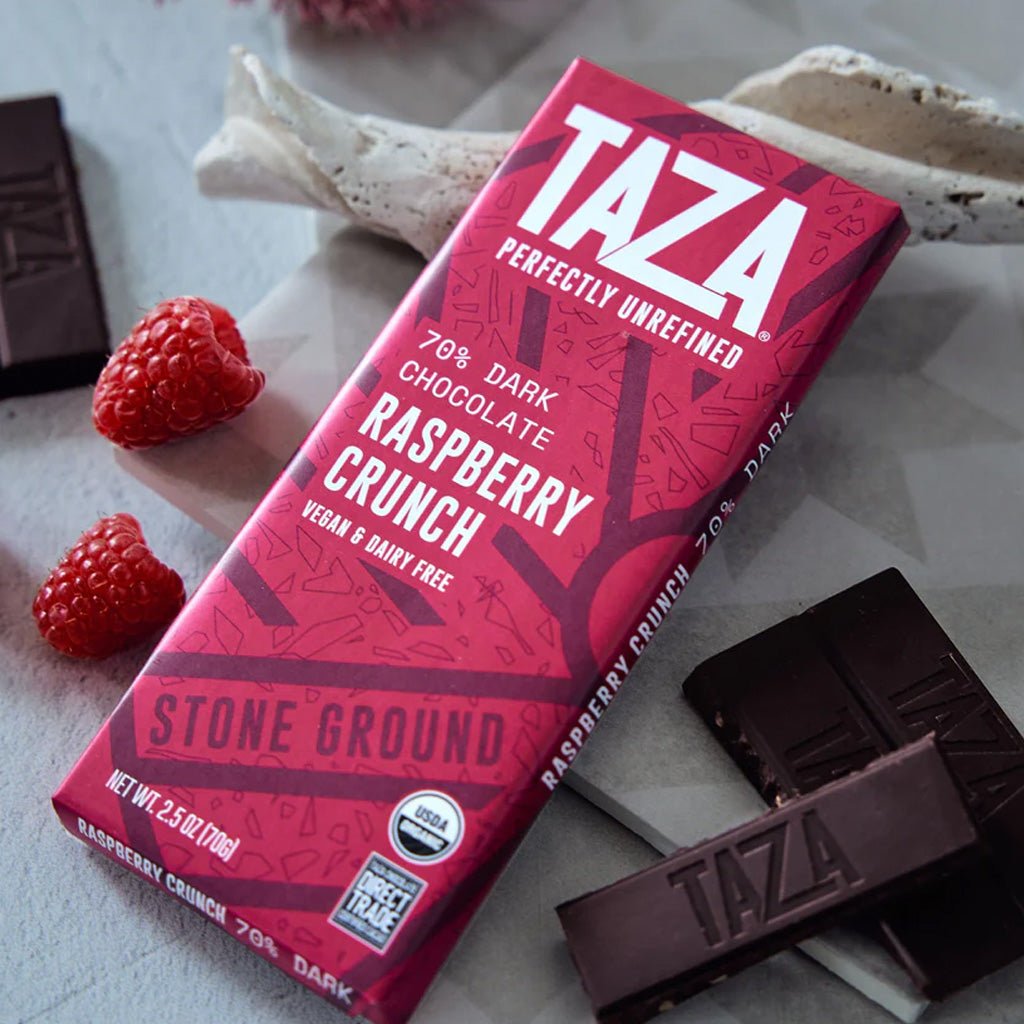 Taza Raspberry Crunch chocolate bar on a light background with raspberries and a piece of chocolate.