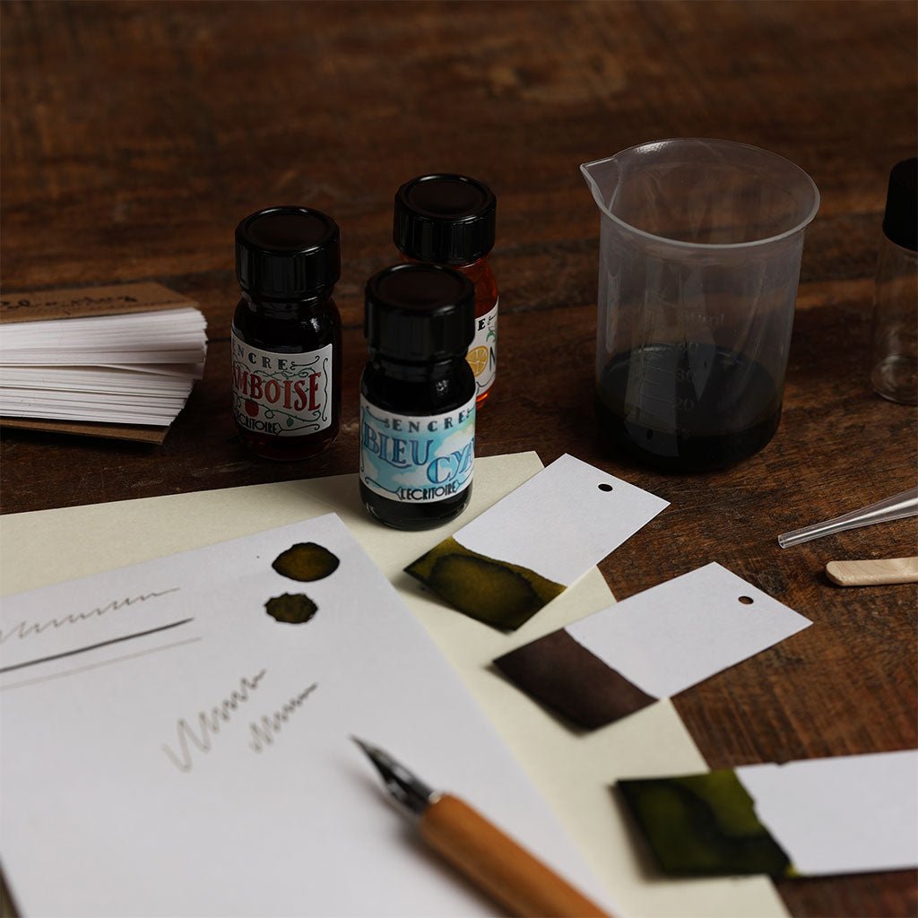 Ink bottles, inkwell, and paper with ink samples on a wooden table