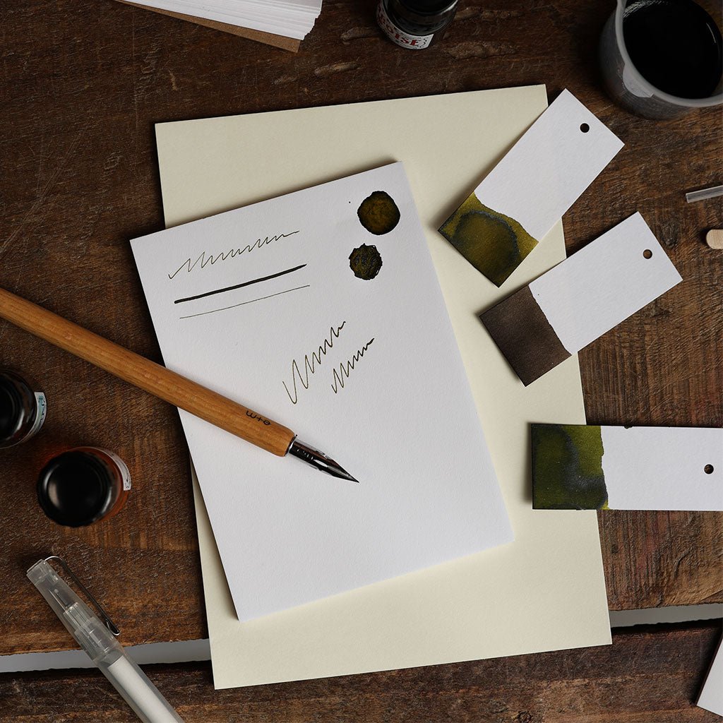Fountain pen with ink bottles and paper on a wooden surface
