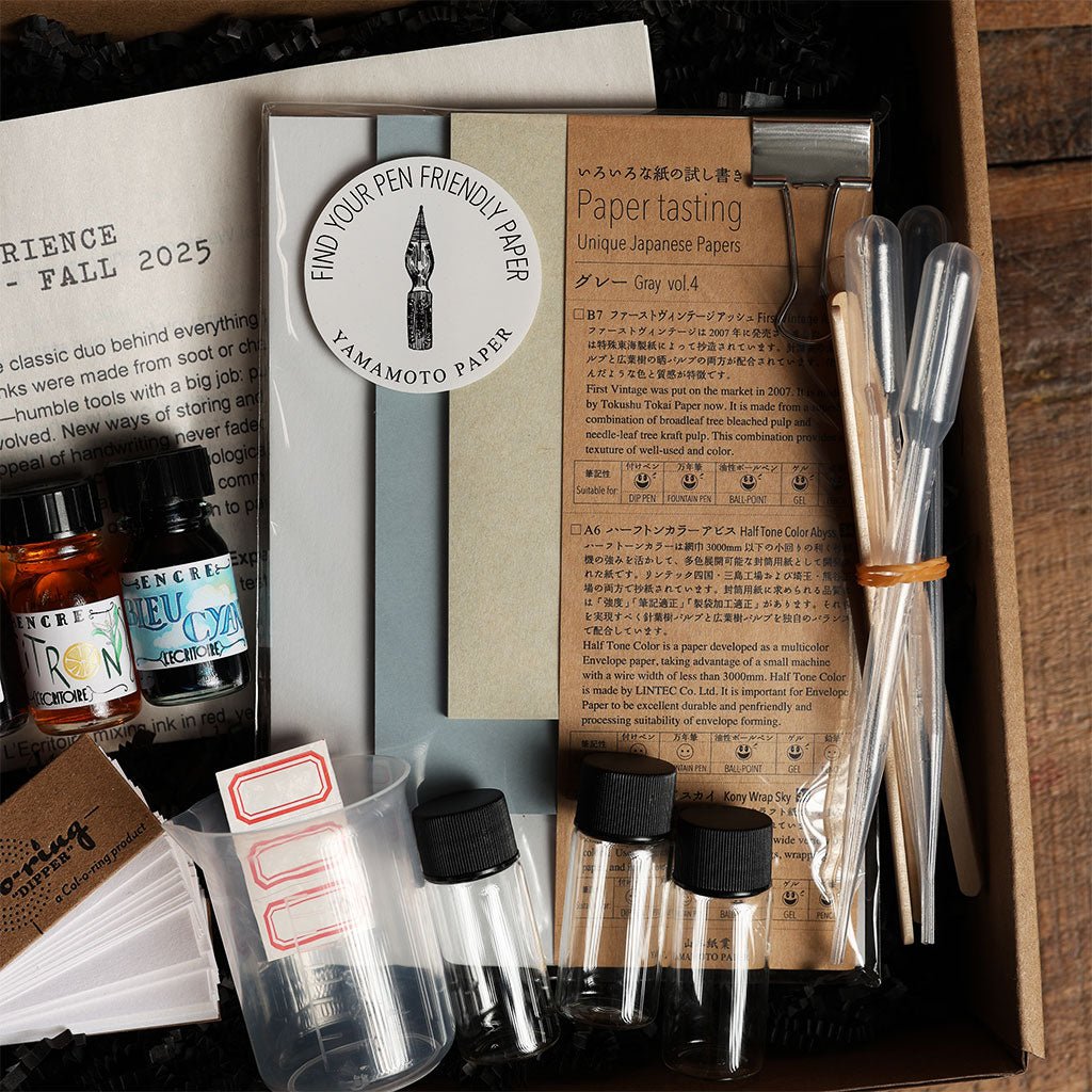 Collection of stationery items including paper, ink, and writing tools in a box.