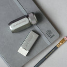Blackwing sharpener and eraser on a gray notebook with a pencil lying next to them.