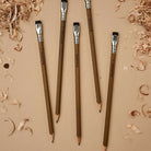 Five Blackwing Volumes 21 pencils on a tan surface, surrounded by wood shavings. 