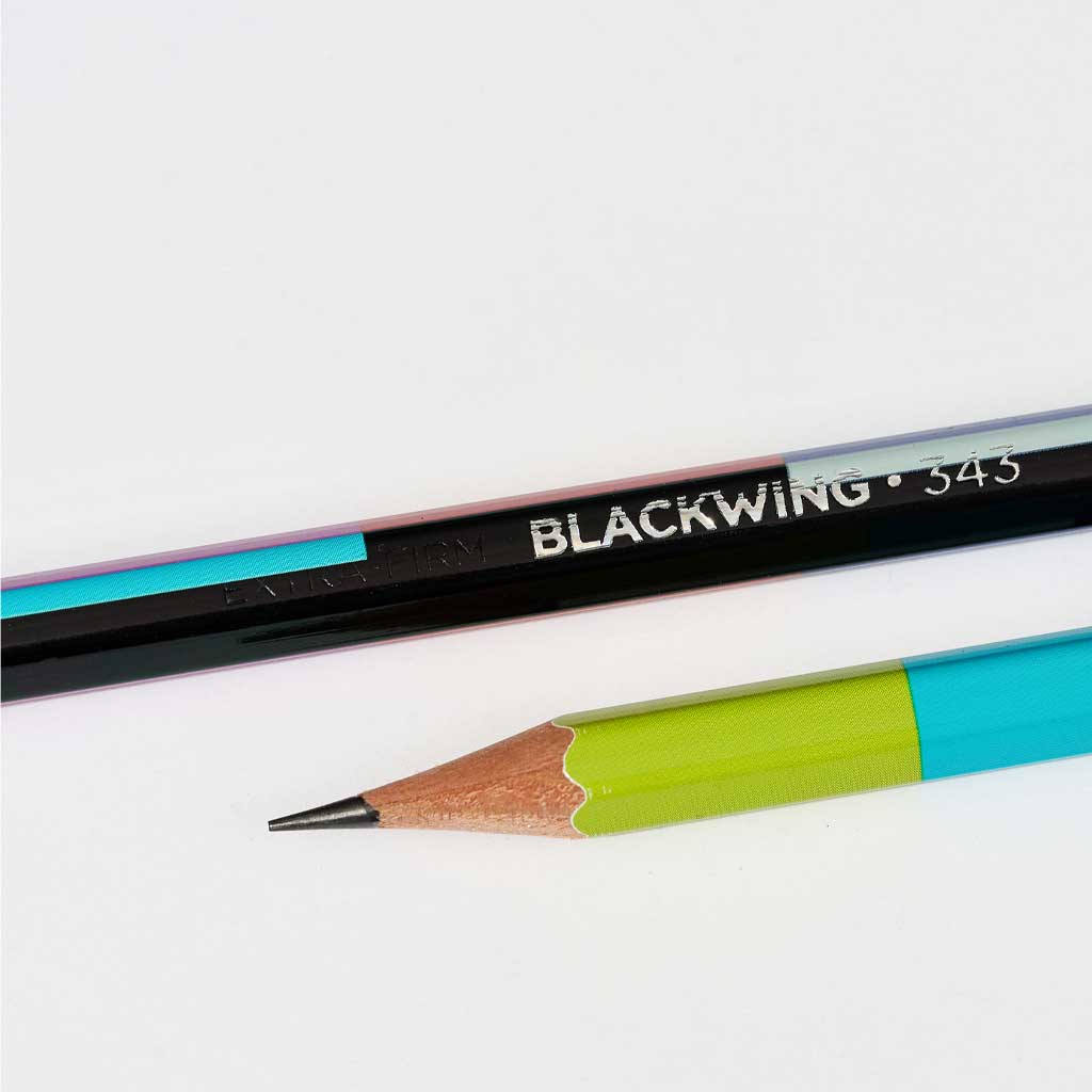 Two pencils, one black with 'Blackwing' branding and the other multicolored, on a white background.