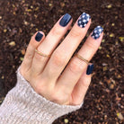 Hand wearing dark navy blue blue maize nail polish on natural background