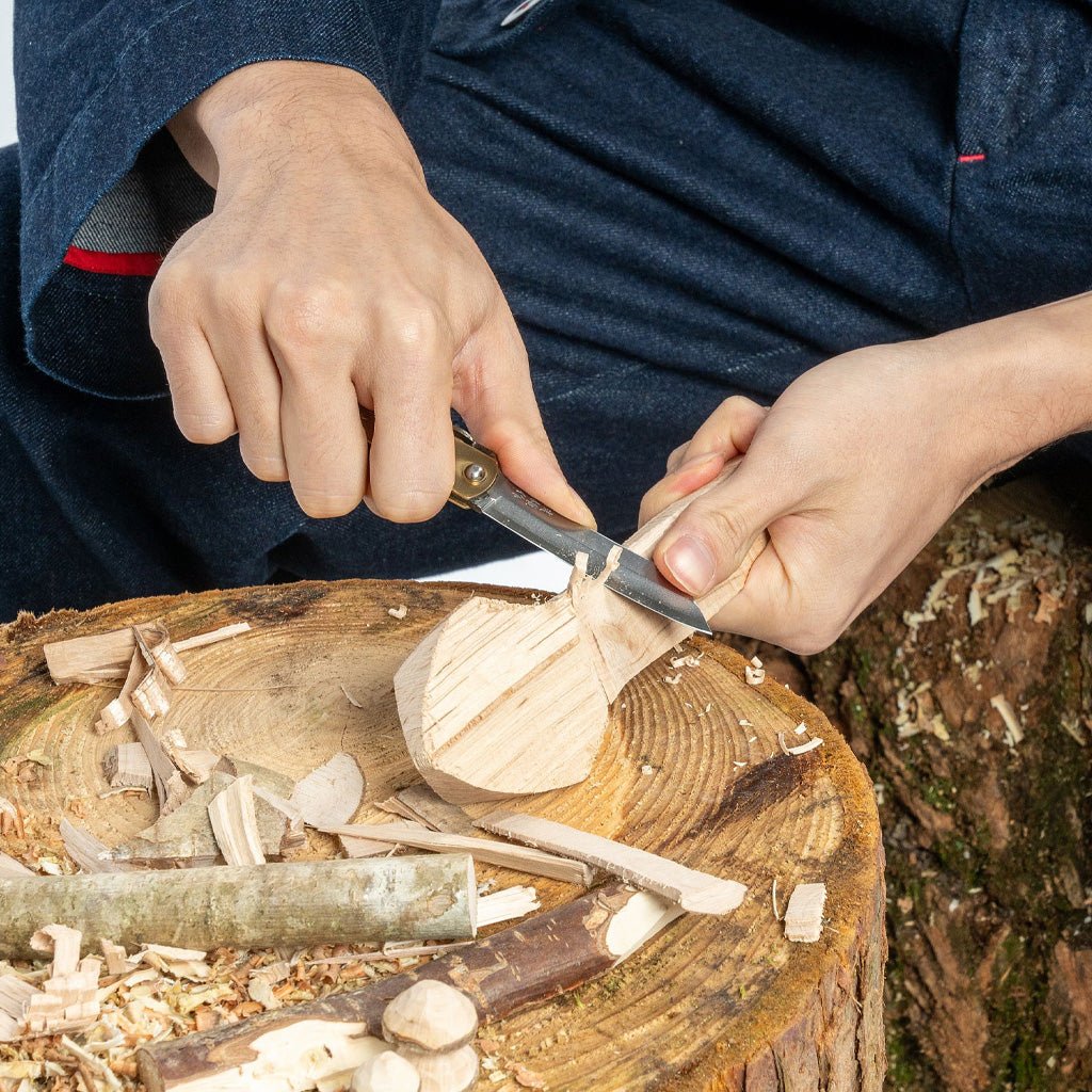 Person carving wood on a tree stump with folding knife