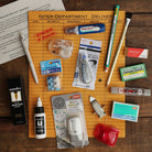 Overhead arrangement of erasers, correction tapes, stain remover, and other stationery on an orange folder and wooden table.