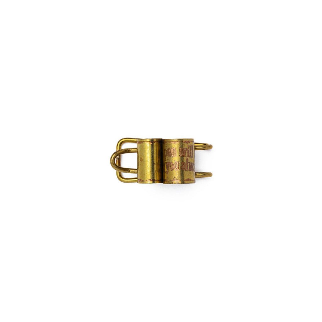 Brass clip with engraved text on a white background