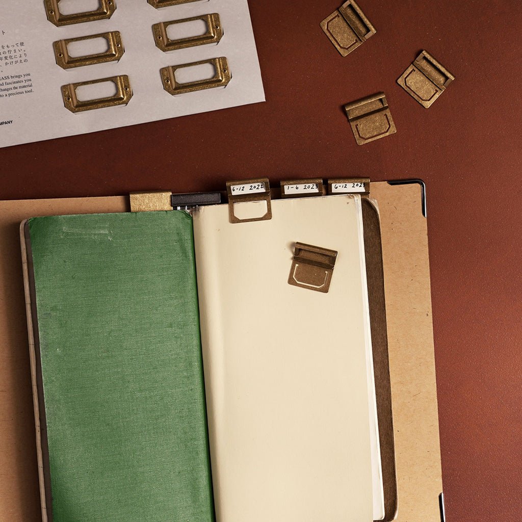 Traveler's notebook with brass index clips on brown background