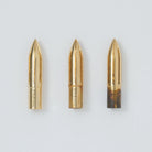 Three brass nibs in various rusting stages on gray background