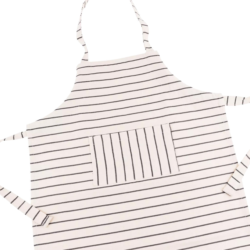 A white cotton apron for children with thin horizontal stripes, featuring a central vertical-striped pocket and hip ties and neck loop, shown on a plain white background.