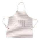 A white cotton apron for children with thin horizontal stripes, featuring a central vertical-striped pocket and hip ties and neck loop, shown on a plain white background.