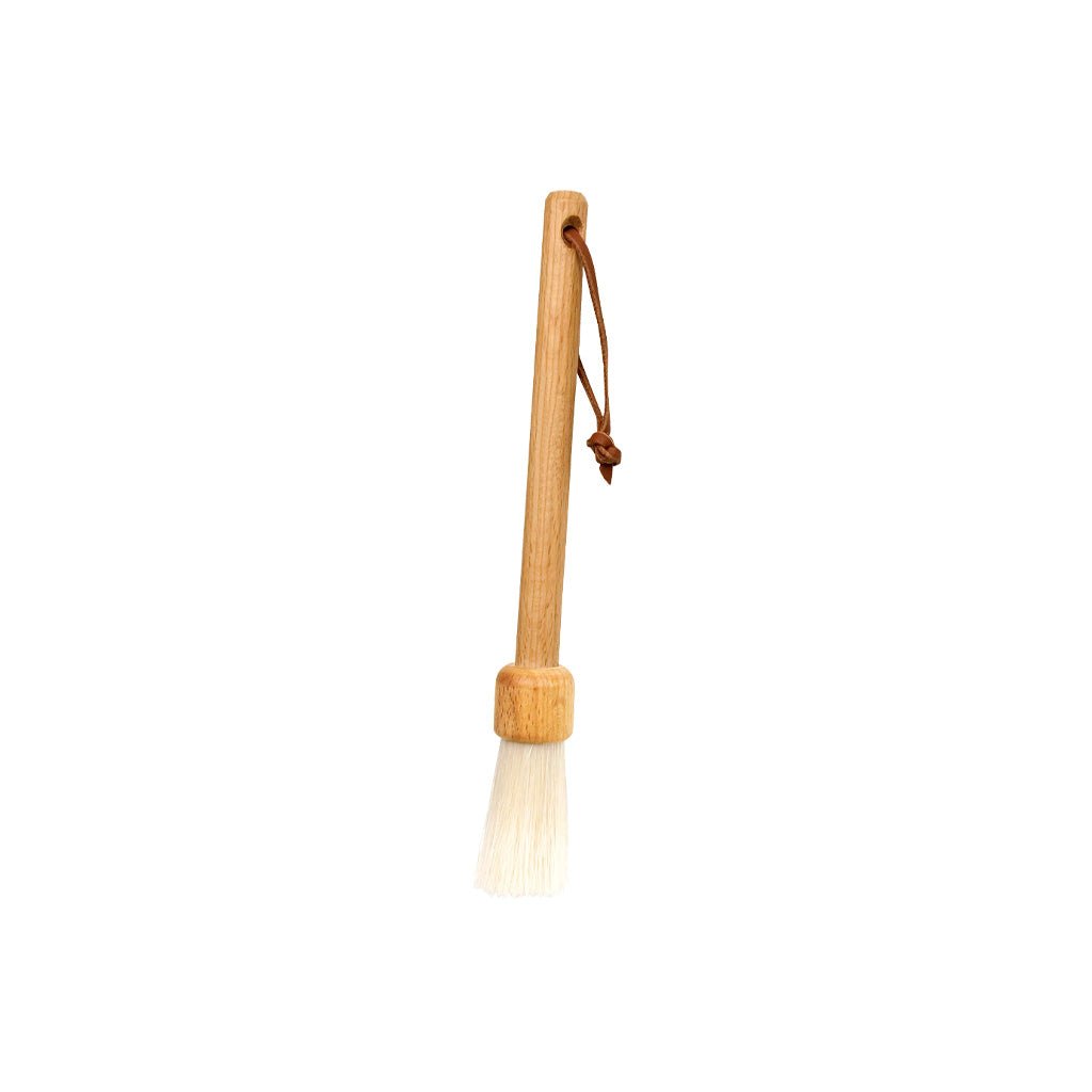 Slender wooden dust brush with light-colored bristles on white background