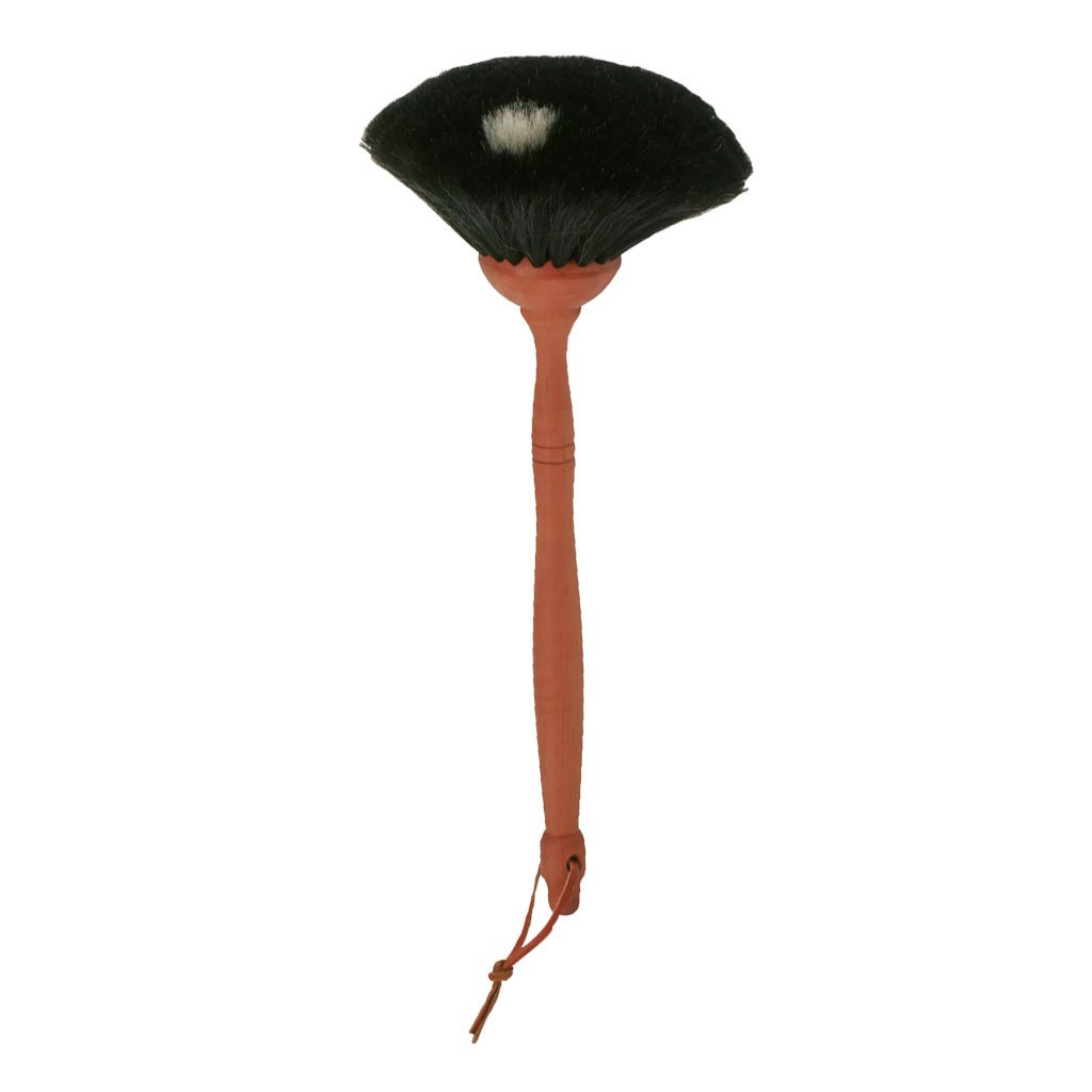 A goat hair dust brush with a pear wood handle and leather loop and black bristles on white background
