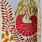 A close-up of unfolded festive paper greeting card featuring a stylized bird in pink and red, surrounded by mistletoe, holly leaves, and berries on a white background.