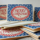 Red and blue Merry Christmas cards standing upright on top of other cards and envelopes.