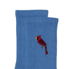 A pair of blue ribbed knit socks stacked on top of each other, featuring a small embroidered cardinal bird on the front sock.