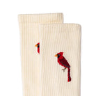 A pair of off-white ribbed crew socks featuring embroidered red cardinal birds on the sides, displayed against a solid white background.