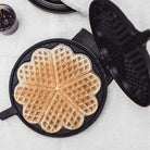 Waffle iron with a freshly made waffle on a light surface