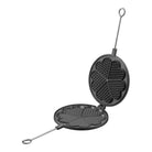 Black cast iron waffle iron open with aluminum handle on white background
