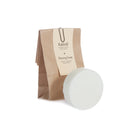 A brown paper bag of Raktval Shaving Soap with a cream-colored oval bar of soap in front, set against a plain white background.