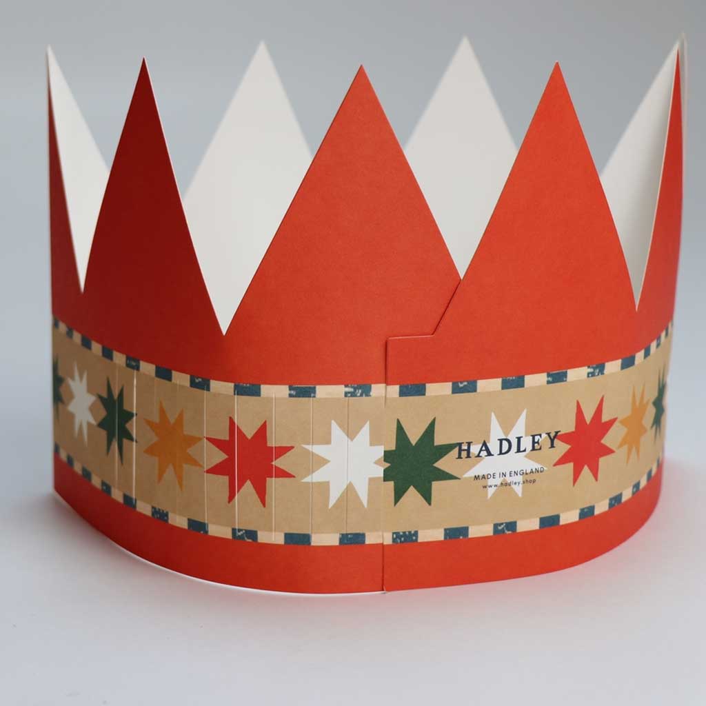 Red and white paper crown with a patterned band featuring stars and the brand 'Hadley'.