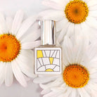 Bottle of citrus perfume oil resting among daisies 