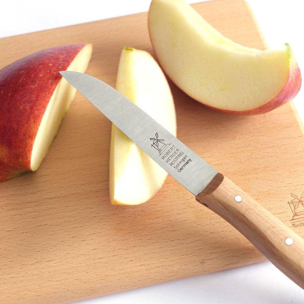 Vegetable knife with wooden handle and windmill logo on a cutting board with apples