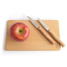 Wooden cutting board with an apple and two knives on a white background