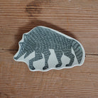 A ceramic wolf-shaped dish with a dark gray hand-drawn style dog illustration on a white base, placed on a rustic wooden surface.