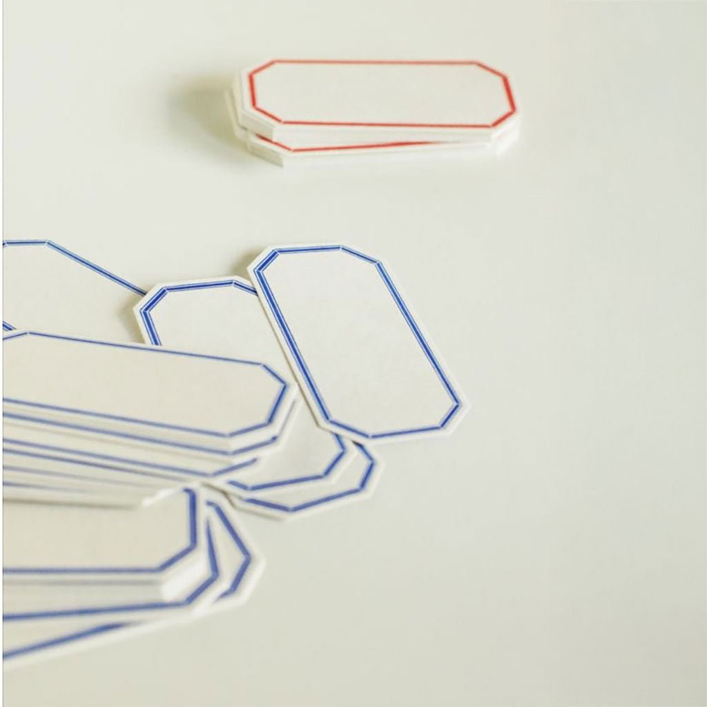 Assorted octagonal-shaped letterpress labels on a cream-colored surface. 