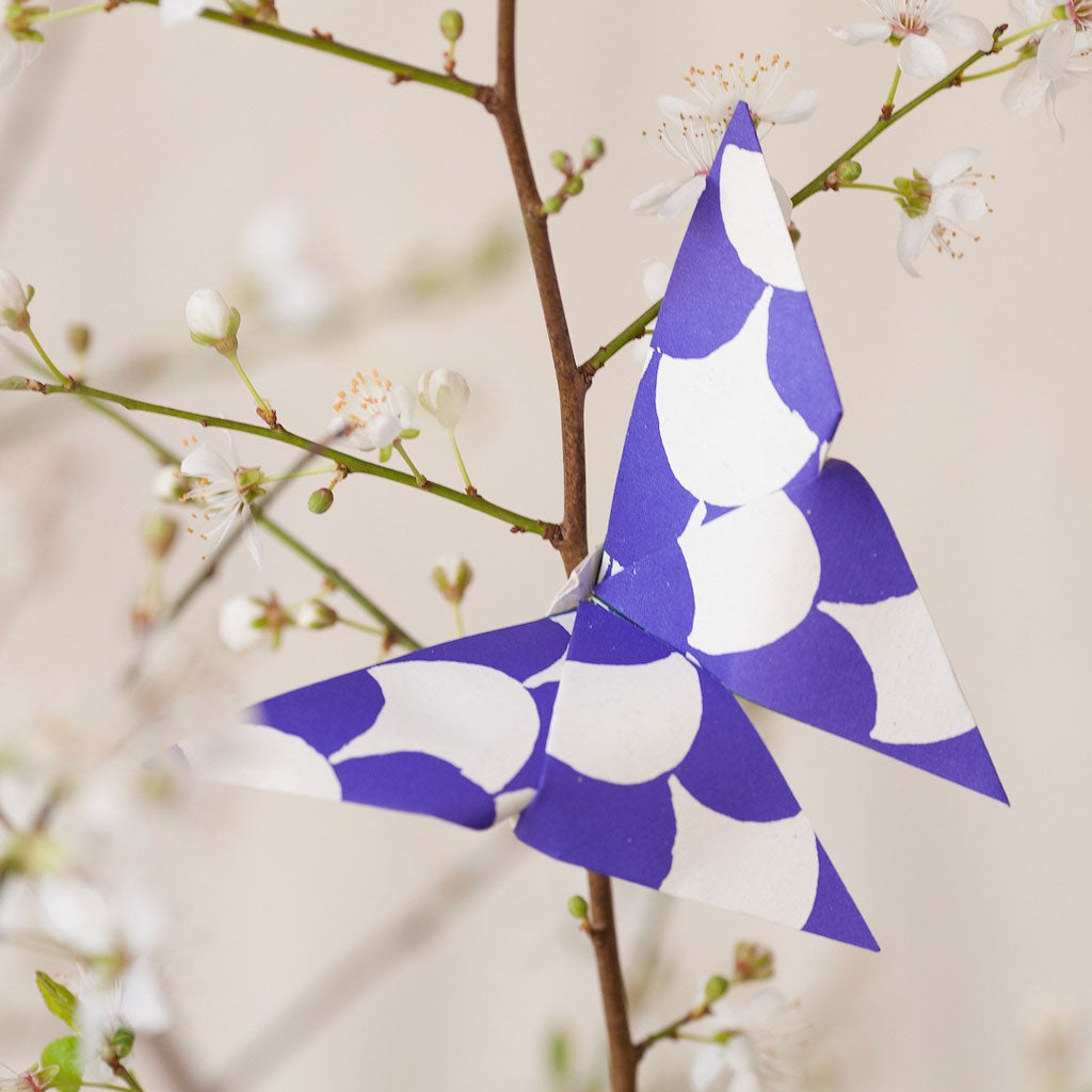 Blue and white origami butterfly on branch