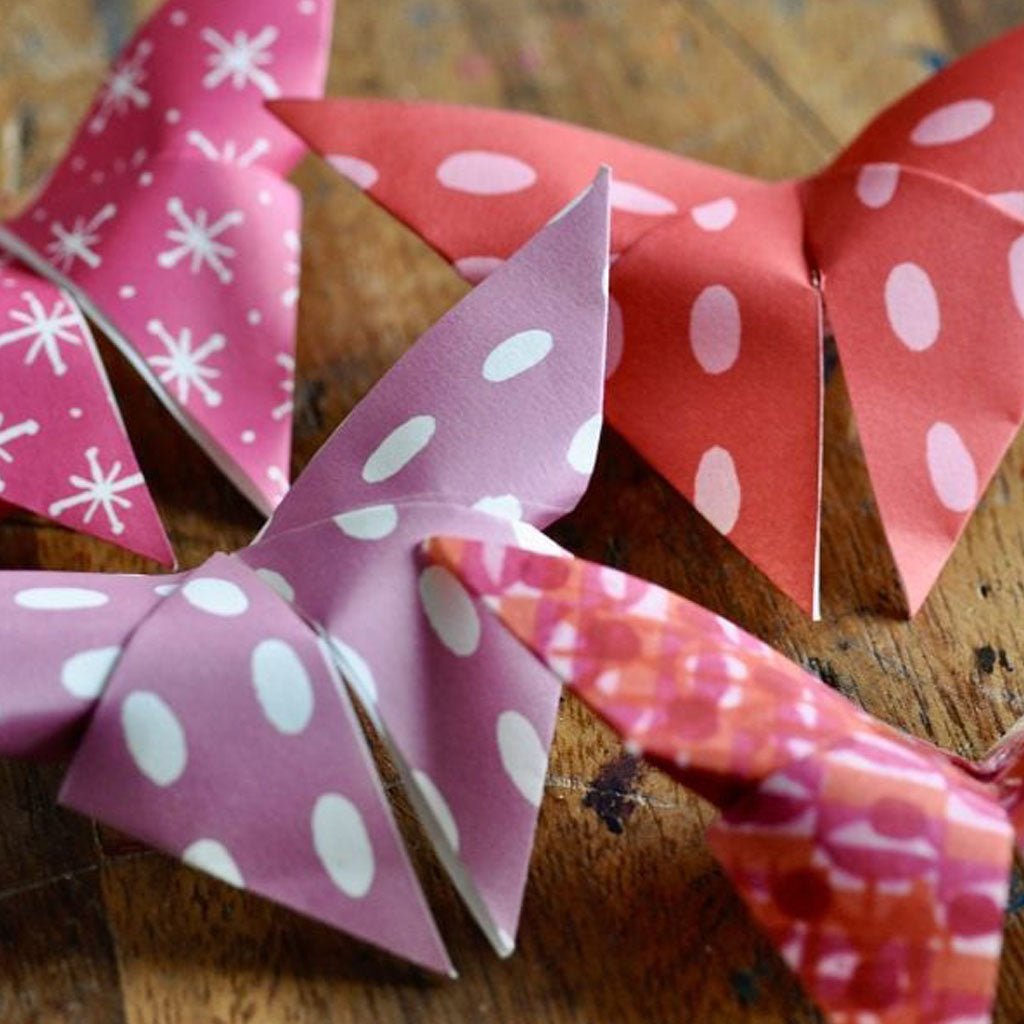 Colorful paper origami butterflies with polka dot patterns on a wooden surface