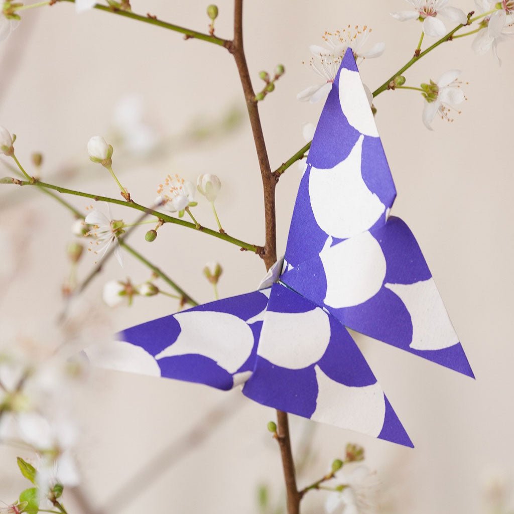 Blue and white origami butterfly on branch