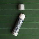 An open coccoina adhesive stick on a green chalkboard 
