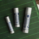 Three coccoina adhesive sticks of different sizes on a green chalkboard 