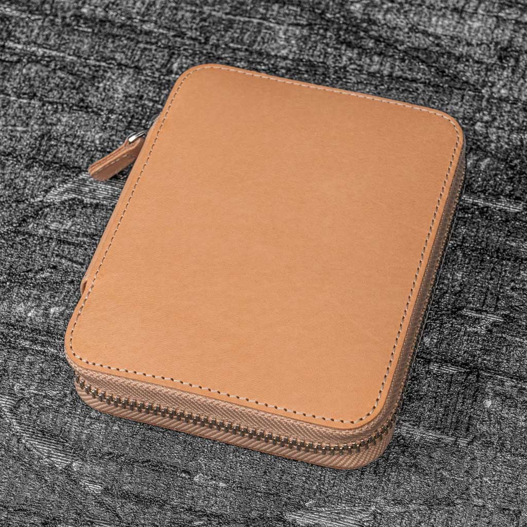 Natural undyed leather zippered pen case on textured surface