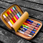 Set of colorful Kaweco pens in a brown leather case on a wooden surface