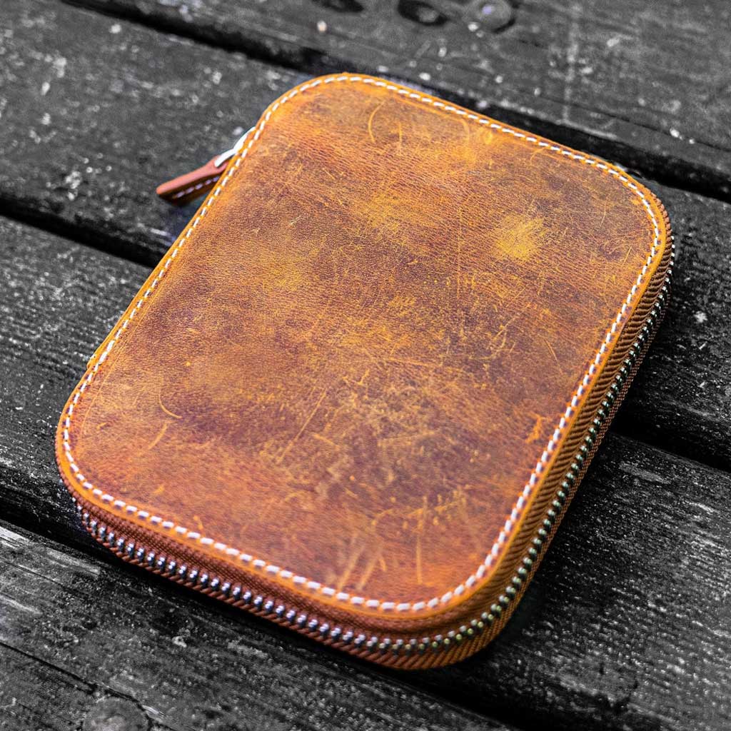 Brown leather zippered pen case on wooden surface