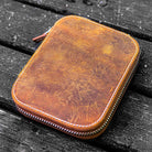 Brown leather zippered pen case on wooden surface