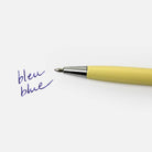 Yellow pen with silver cap on a white background, writing the word 'bleu blue'.