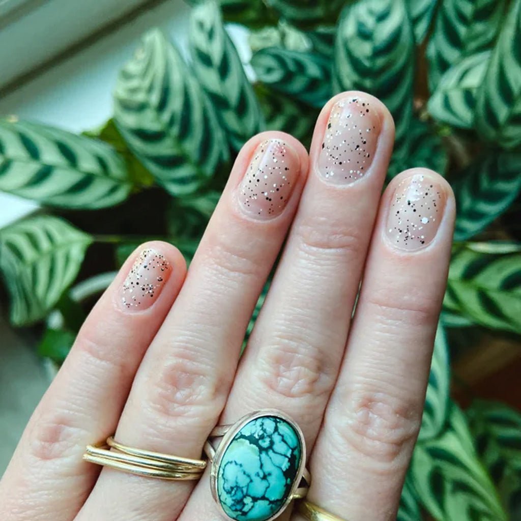 Hand wearing cookies and cream sheer glittery nail polish