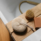 Natural cleaning tools including a loofah, brush, and soap bar on a wooden block.