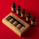 Set of brown bottles of cocktail mixers and a cardboard box on a red background