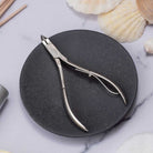 Cuticle nippers on a black stone surface with seashells in the background