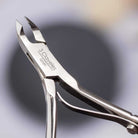 Metal cuticle nipper with '3 Claveles' branding on a blurred background