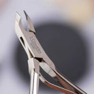 Metal nail clippers with '3 Claveles' branding on a blurred background
