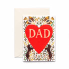 A greeting card with a large red heart and the word 'DAD' in white letters, surrounded by a floral and animal pattern. The card is held by a white envelope.