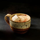 Mug of hot cocoa with marshmallow on dark background.