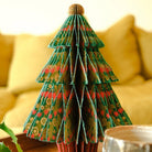 Paper tree decoration open, in front of yellow couch.